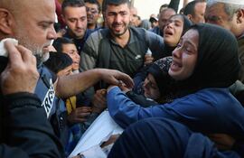 The widow (R) of Hamza Wael Dahdouh, a journalist with the Al Jazeera television network, and his father Al Jazeera's bureau chief in Gaza, Wael Al-Dahdouh (L) mourn over his body during his funeral, after he was killed in a reported Israeli air strike, in Rafah in the Gaza Strip on January 7, 2024. Dahdouh, who was himself wounded in the arm, lost his wife and two other children in Israeli bombardment in the initial weeks of the war. (Photo by AFP)