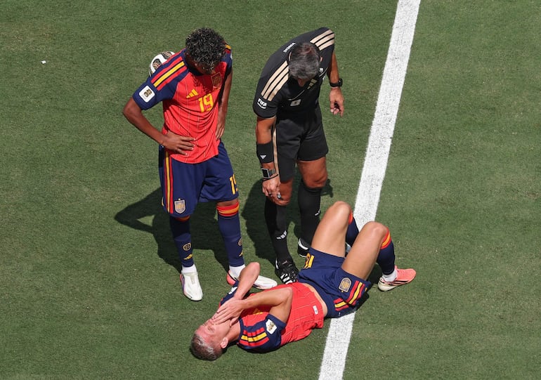El árbitro Slavko Vincic (arriba d.) y el español Lamine Yamal (arriba izq.) revisan al español Dani Olmo, quien yace en el césped durante el partido de la final de la Copa Mundial de la FIFA 2026 entre España y Argentina, en Nueva Jersey, EE. UU..