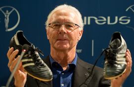 Fotografía de archivo del exfutbolista y entrenador alemán Franz Beckenbauer, sosteniendo a entrenadores de fútbol durante una conferencia de prensa en Stuttgart, Alemania, el 27 de enero de 2013, reeditada el 8 de enero de 2024.