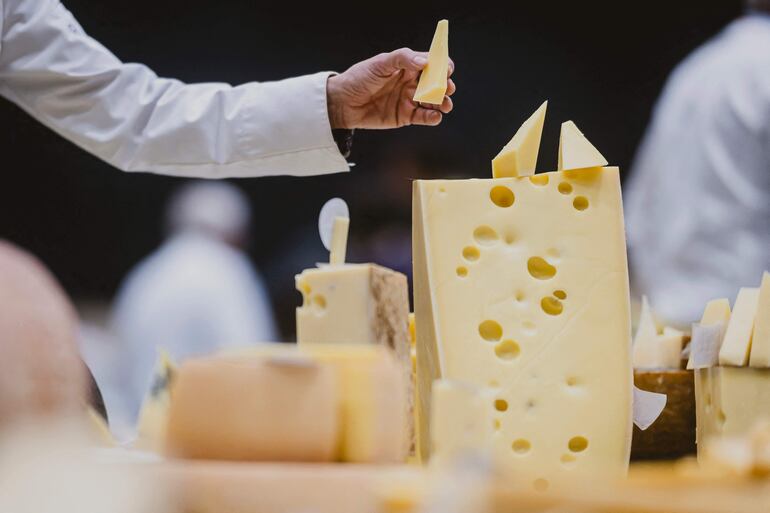 Una persona está de pie junto a un trozo de queso emmental durante la 37ª edición de los World Cheese Awards, organizados por el Guild of Fine Food, en Berna, el 13 de noviembre de 2025.