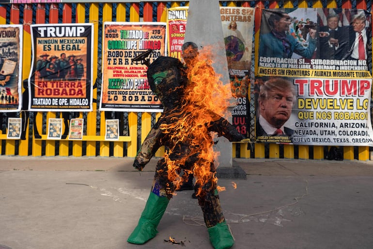 El defensor de los derechos de los migrantes Sergio Tamai quema una piñata con la imagen de un agente del Servicio de Inmigración y Control de Aduanas (ICE) durante una protesta contra las políticas migratorias del presidente estadounidense Donald Trump en el muro fronterizo entre México y Estados Unidos en Playas de Tijuana, Baja California, México.