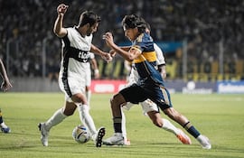 Raúl Cáceres (i), jugador de Olimpia, disputa el balón en un partido amistoso ante Boca Juniors en el estadio Único de San Nicolás, en San Nicolás de los Arroyos, Argentina.