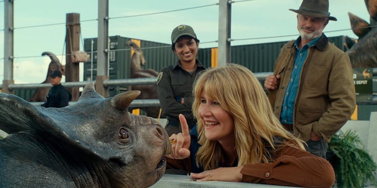 Laura Dern y Sam Neill en el set, con Dern usando un sombrero y ambos sonriendo, rodeados de ambiente cinematográfico.