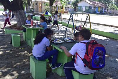 Niños utilizan mesadas y bancos instalados bajo árboles para almorzar en la Escuela Básica N° 612 Cerro Corá, de Lambaré.