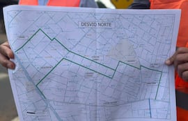 Avelino Martínez con chaleco de seguridad naranja, sosteniendo un mapa titulado 'DESVIO NORTE' en un entorno urbano.