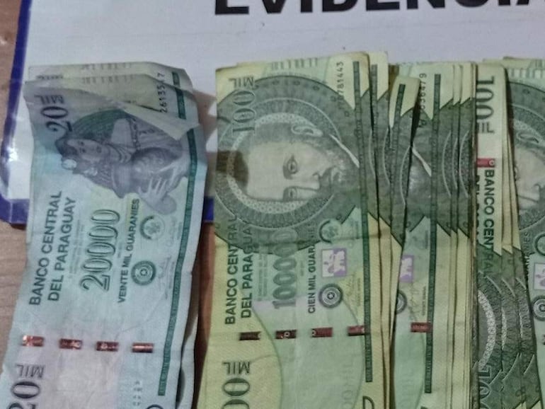 Billetes paraguayos dispuestos sobre una superficie de madera, acompañados de un documento con la palabra 'EVIDENCIAS'.
