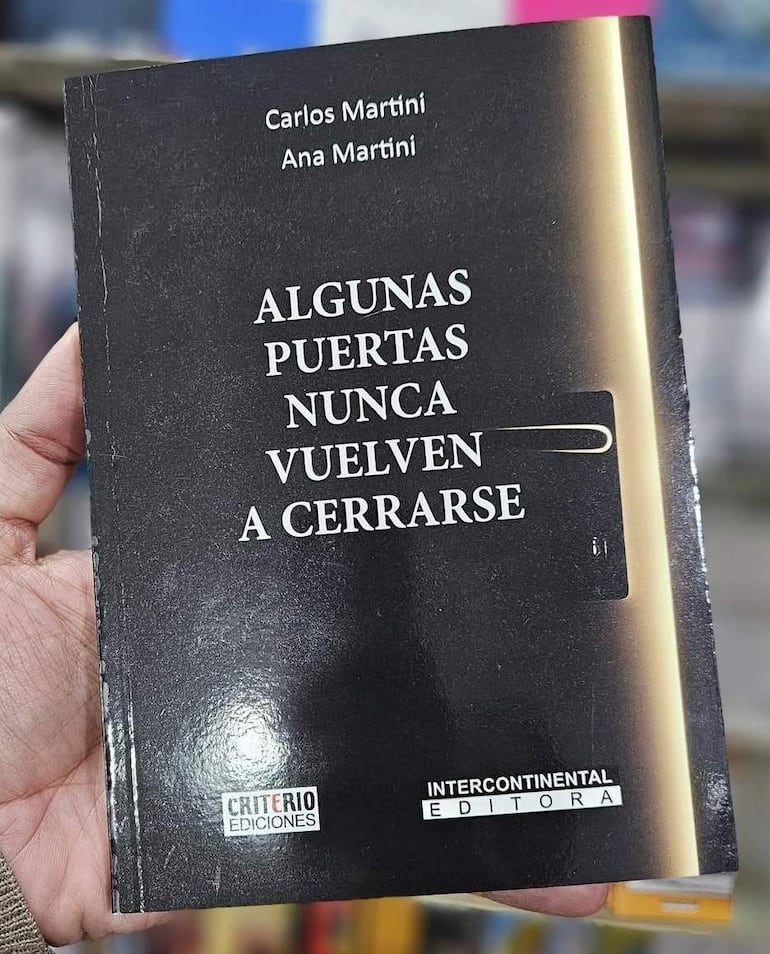 Libro 'Algunas puertas nunca vuelven a cerrarse' de Carlos y Ana Martini, sostenido por una mano de fondo negro y texto blanco.