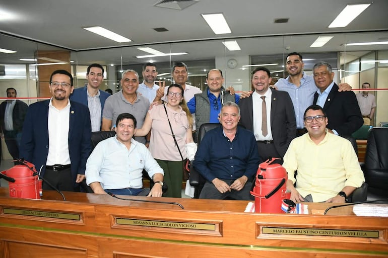 Luifer Bernal y diez personas sonriendo en un entorno formal, algunos en sillas, otros de pie, mostrando gestos amistosos.