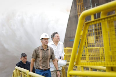 Santiago Peña con camiseta clara y sombrero blanco lidera la visita, rodeado de dos hombres en entorno industrial con grandes estructuras de metal.