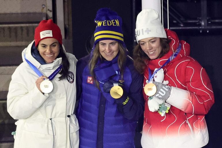 La medallista de plata Heidi Weng de Noruega, la medallista de oro Ebba Andersson de Suecia y la medallista de bronce Nadja Kaelin de Suiza posan en el podio de la prueba de esquí de fondo libre con salida en masa de 50 km femenino.