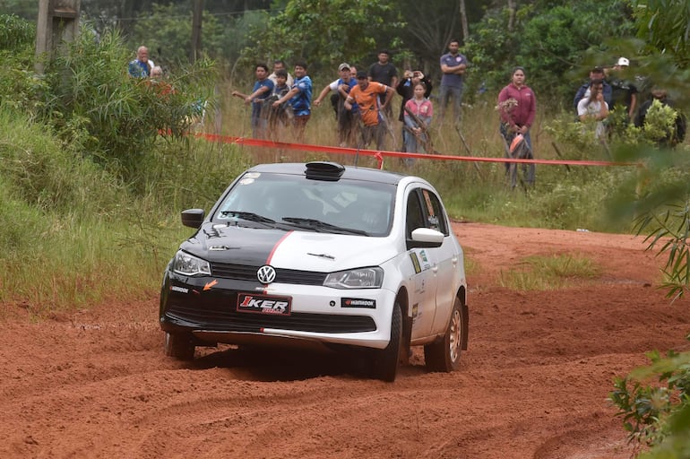 Un Volkswagen en acción sobre terreno de tierra roja, mientras espectadores observan emocionados, algunos con cámaras.