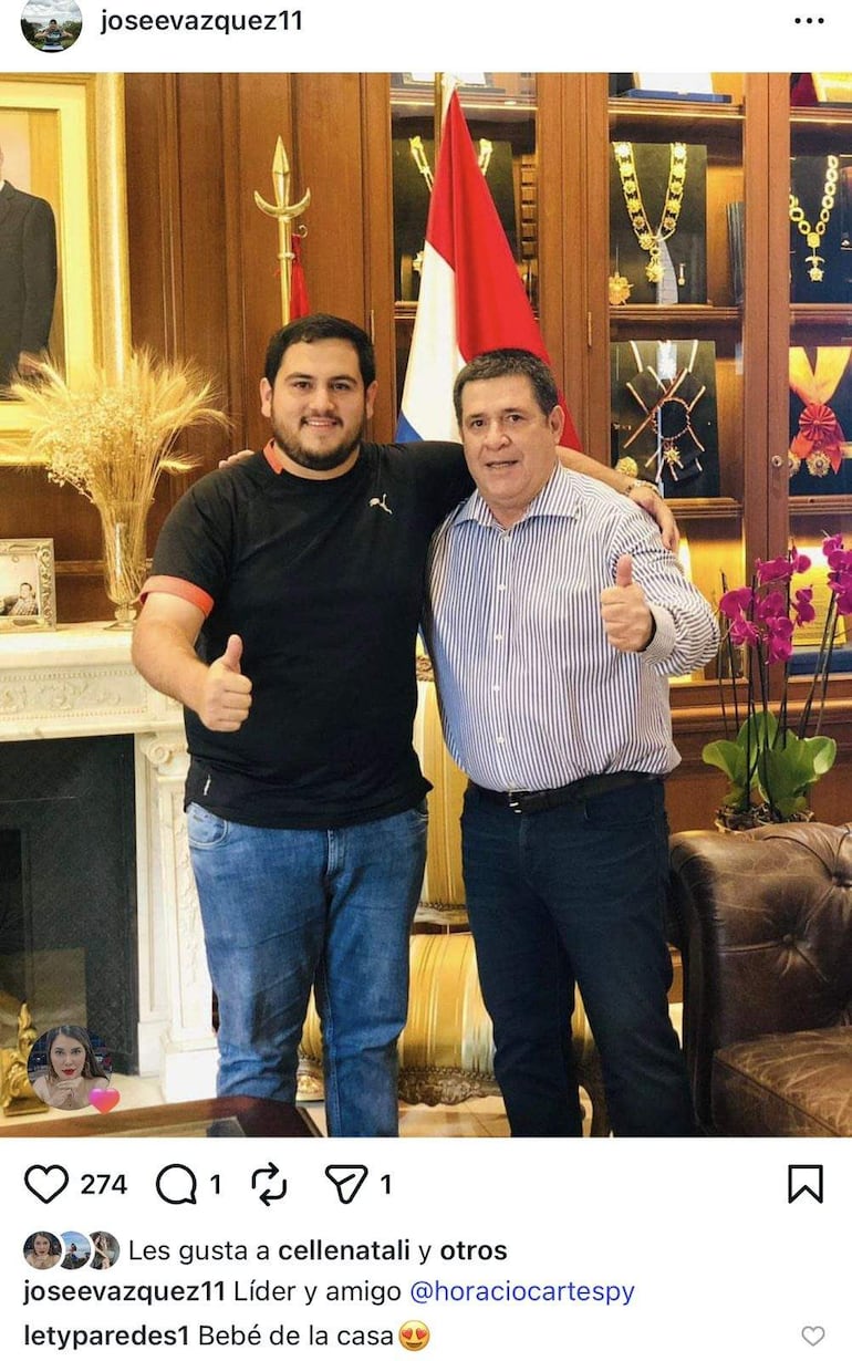 Horacio Cartes y José Emilio Vázquez Acosta sonríen en oficina decorada, haciendo pulgar arriba y vistiendo trajes formales.