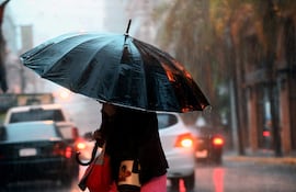una sra con paragua cruza la calle tras intensa lluvia ,centro de asunciòn