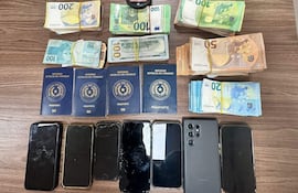 Cuatro pasaportes del Mercosur y varios teléfonos móviles, algunos dañados, sobre una superficie de madera.