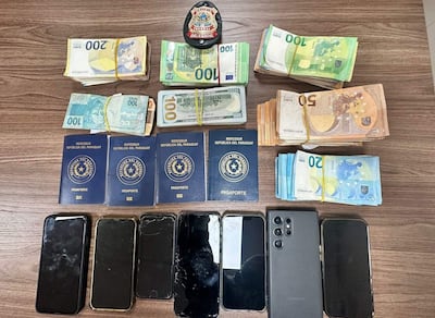 Cuatro pasaportes del Mercosur y varios teléfonos móviles, algunos dañados, sobre una superficie de madera.