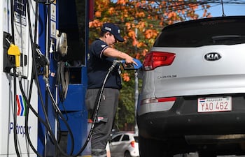 Hombre con camiseta negra repostando combustible en un Kia Sportage plateado en estación Petropar, árboles al fondo.