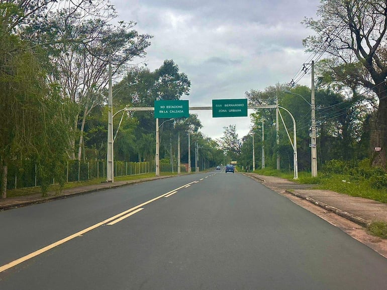 Calle de San Bernardino con cielo nublado, cartel de zona urbana y vehículo en la distancia.