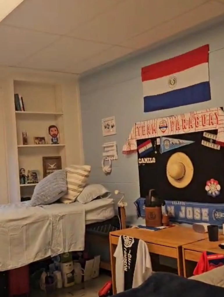 La habitación de Camilo Camilo Villalba en su universidad con la bandera de Paraguay y un termo de tereré de fondo.