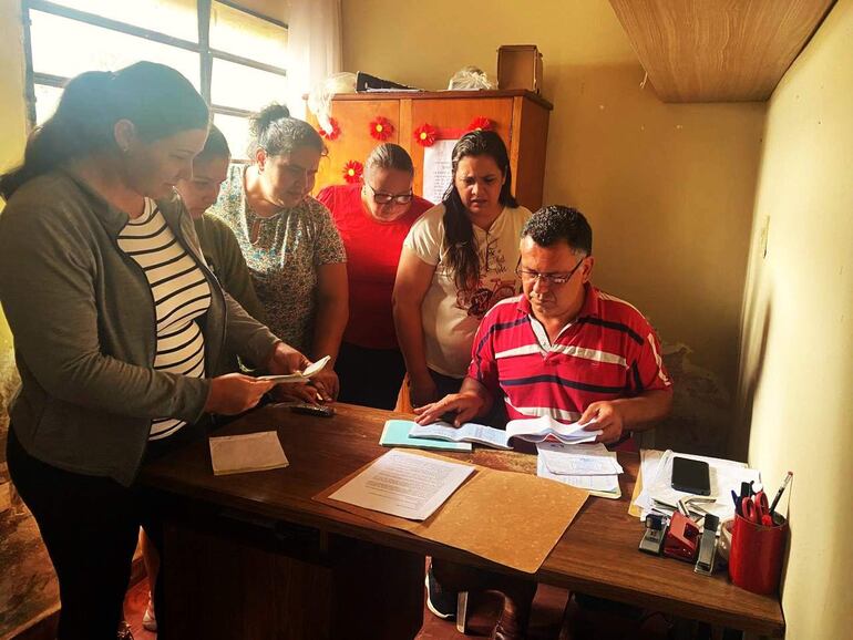 Un grupo de seis personas revisa documentos en una oficina, abordando preocupaciones sobre la deuda con ANDE y el atraso salarial.