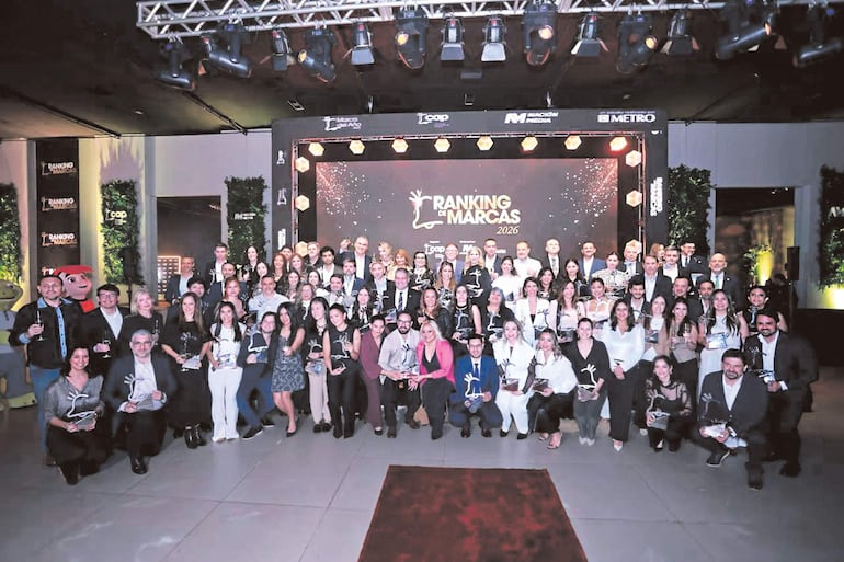 Asistentes en traje formal celebran el Ranking de Marcas 2026, mostrando trofeos y sonrisas en un ambiente iluminado.