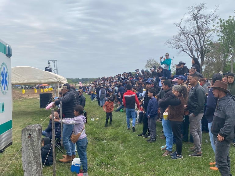 Multitud de personas, incluidos niños con algodón de azúcar, disfrutando de evento al aire libre con sombreros y ropa variada.