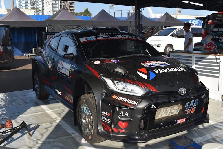 Vehículo del MSi Racing Team en carpa negra, con emblemas de patrocinadores y mecánicos trabajando en el fondo.
