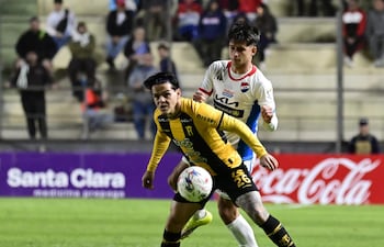 El volante ofensivo de Guaraní, Diego Fernández intenta proteger el esférico ante la marca del lateral de Nacional, Juan Sebastián Vargas.