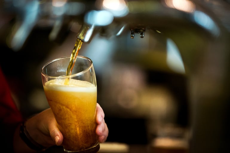 Un bartender sirve un vaso de cerveza.