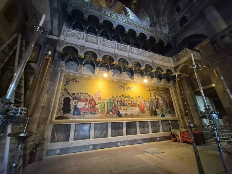 Interior del Santo Sepulcro en Jerusalén, con mosaico en la pared y detalles ornamentales en columnas y arcos.