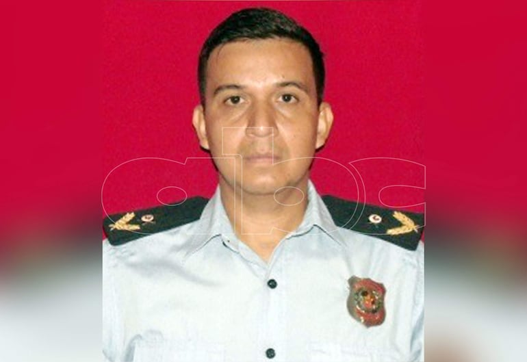 Derlis Ramón Cáceres Talavera en uniforme celeste con insignias, frente a un fondo rojo liso, con expresión tranquila.