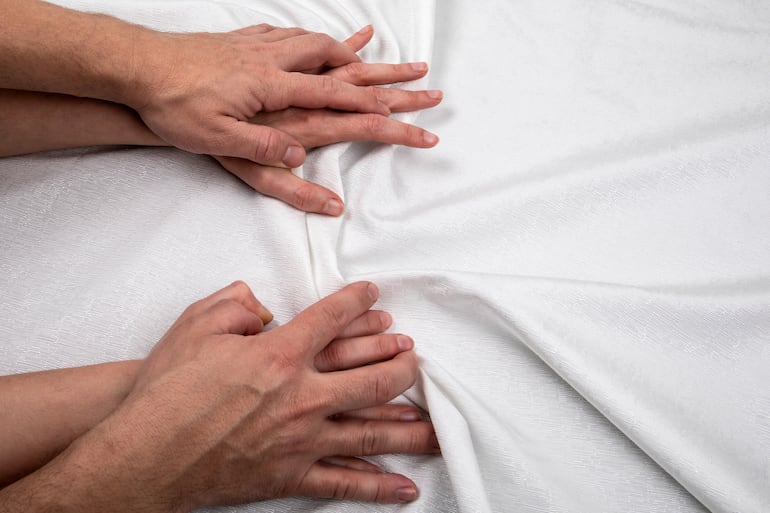 Pareja en la cama. Manos.