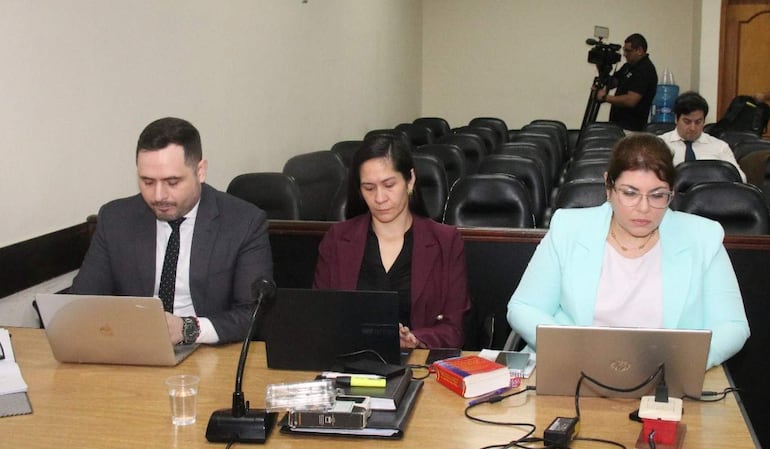 Silvio Corbeta, Verónica Valdez y Yeimy Adle concentrados en sus laptops, en una sala de audiencias con sillas vacías.