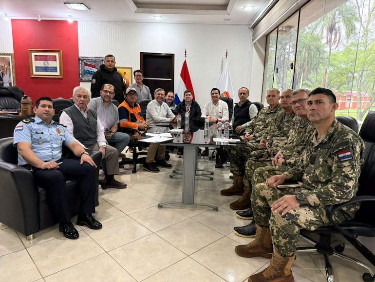 Hombres en uniforme militar y policial discuten en conferencia con banderas paraguayas, rodeados de botellas de agua.