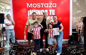 Julio Enciso con camiseta clara sonríe entre niños con dibujos, en ambiente con decoraciones rojas y confeti en el suelo.
