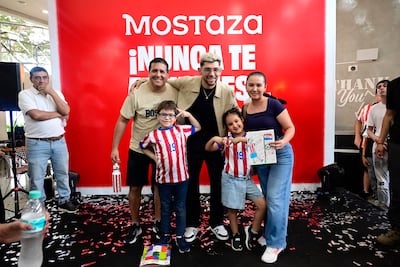 Julio Enciso con camiseta clara sonríe entre niños con dibujos, en ambiente con decoraciones rojas y confeti en el suelo.