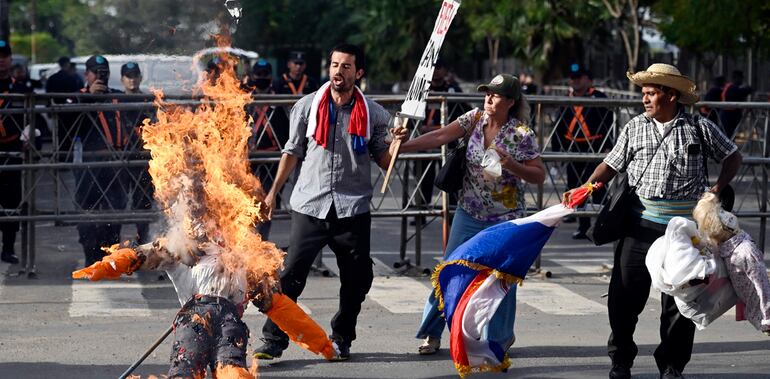 Un manifestante quema el muñeco de “Horacio” Cartes vestido con el “mameluco naranja”.