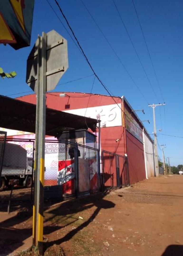 Edificio rojo en área urbana, acceso con reja, sin personas visibles.