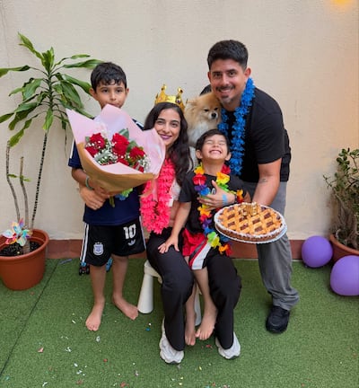 Niño con ramo de flores, mujer sonriente con perro, niño sentado feliz y hombre con postre en un entorno festivo.