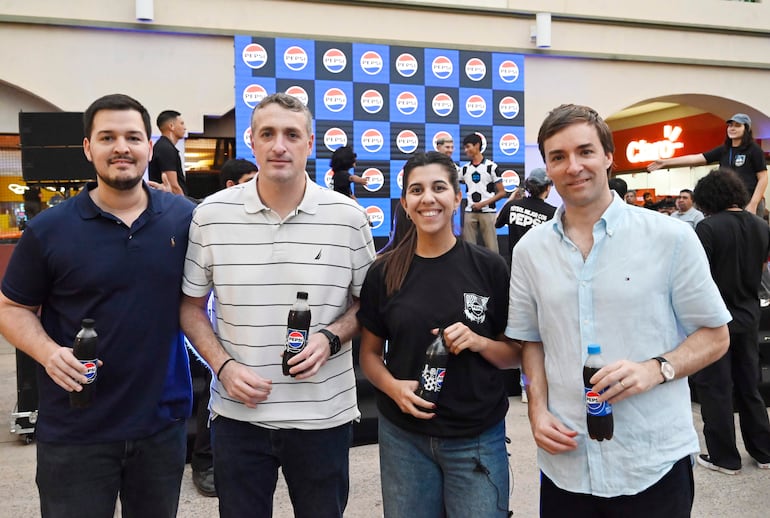 Cuatro personas sonríen sosteniendo botellas de Pepsi, con un gran cartel de la marca de fondo en un evento en Pinedo Shopping.