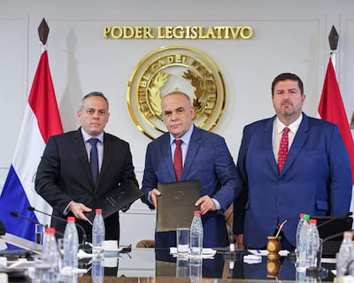 Camilo Benítez con traje azul claro, Basilio Núñez en traje oscuro y Patrick Kemper en traje azul oscuro, en ambiente formal del Poder Legislativo.