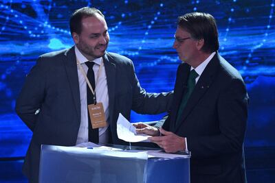 El expresidente de Brasil, Jair Bolsonaro (d) conversa con uno de sus hijos, Carlos Bolsonaro (d).