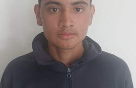 Joven de 17 años con cabello oscuro y serio, vestido con chaqueta deportiva oscura, frente a un muro blanco.