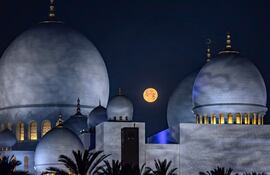 La luna poniente es fotografiada sobre la Gran Mezquita Sheikh Zayed en Abu Dabi el 14 de marzo de 2025, durante el sagrado mes de ayuno del Ramadán en el islam.