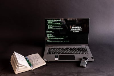 Ordenador portátil con código en pantalla oscuro, libreta y bolígrafo a un lado, sin personas presentes.