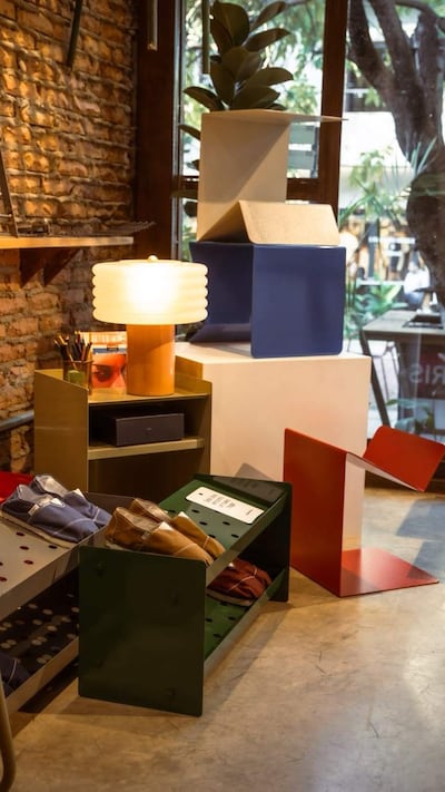 Muestra de diseño con lámpara curvilínea y estanterías de zapatos organizados en un showroom iluminado.