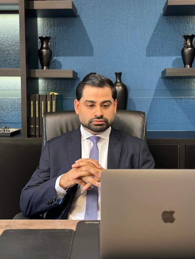 Marcelo Silva sentado en su oficina, vistiendo traje oscuro y corbata púrpura, concentrado frente a su laptop.