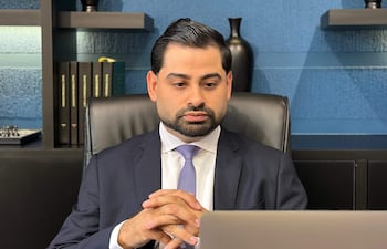 Marcelo Silva sentado en su oficina, vistiendo traje oscuro y corbata púrpura, concentrado frente a su laptop.