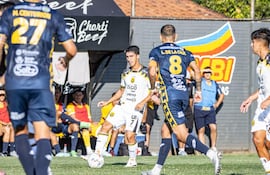 El volante de Guaraní, Agustín Manzur de transporta el esférico ante la presencia del mediocampista y capitán del Sportivo Trinidense, Luis de la Cruz, en el duelo por la segunda fecha del torneo Apertura 2026.