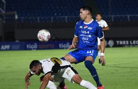 Este fue el segundo último partido de Antonio Bareiro en el equipo de Olimpia. En la foto, el Demonio no puede ante la marca de Gustavo Caballero, justamente el que aprovechó el penal convertido por Bareiro.
