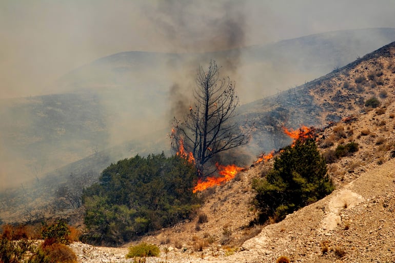 Un incendio quema árboles y vegetación baja en el pueblo de Vati, en la isla de Rodas, Grecia, el 25 de julio de 2023. Los incendios más duros hasta ahora se encuentran en Rodas y Corfú, dijo el 25 de julio el portavoz de la Brigada de Bomberos, Yiannis Artopios, mientras que los otros incendios se han reavivado.